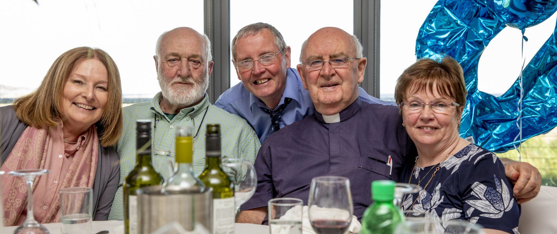 A group of people are sitting at a table with wine bottles and glasses.