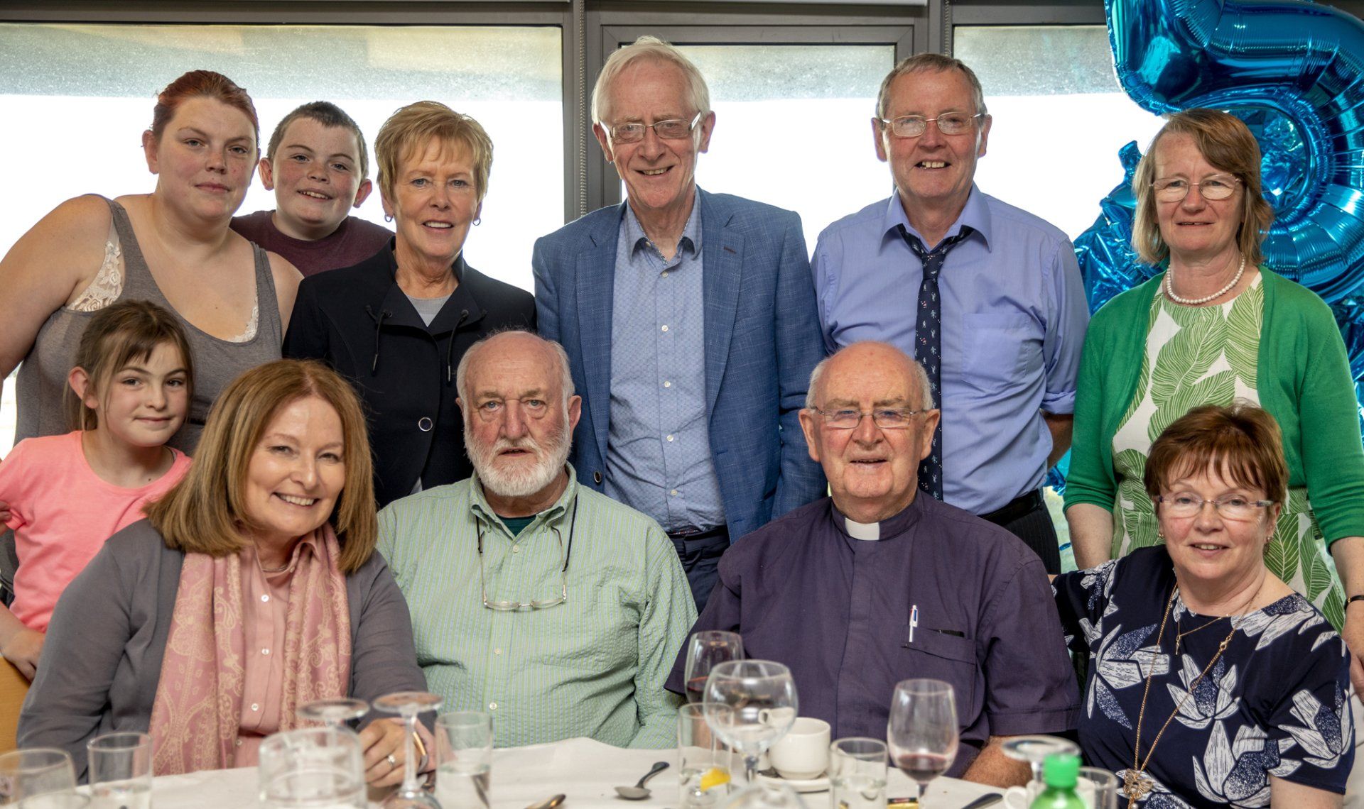 A group of people are posing for a picture while sitting at a table.
