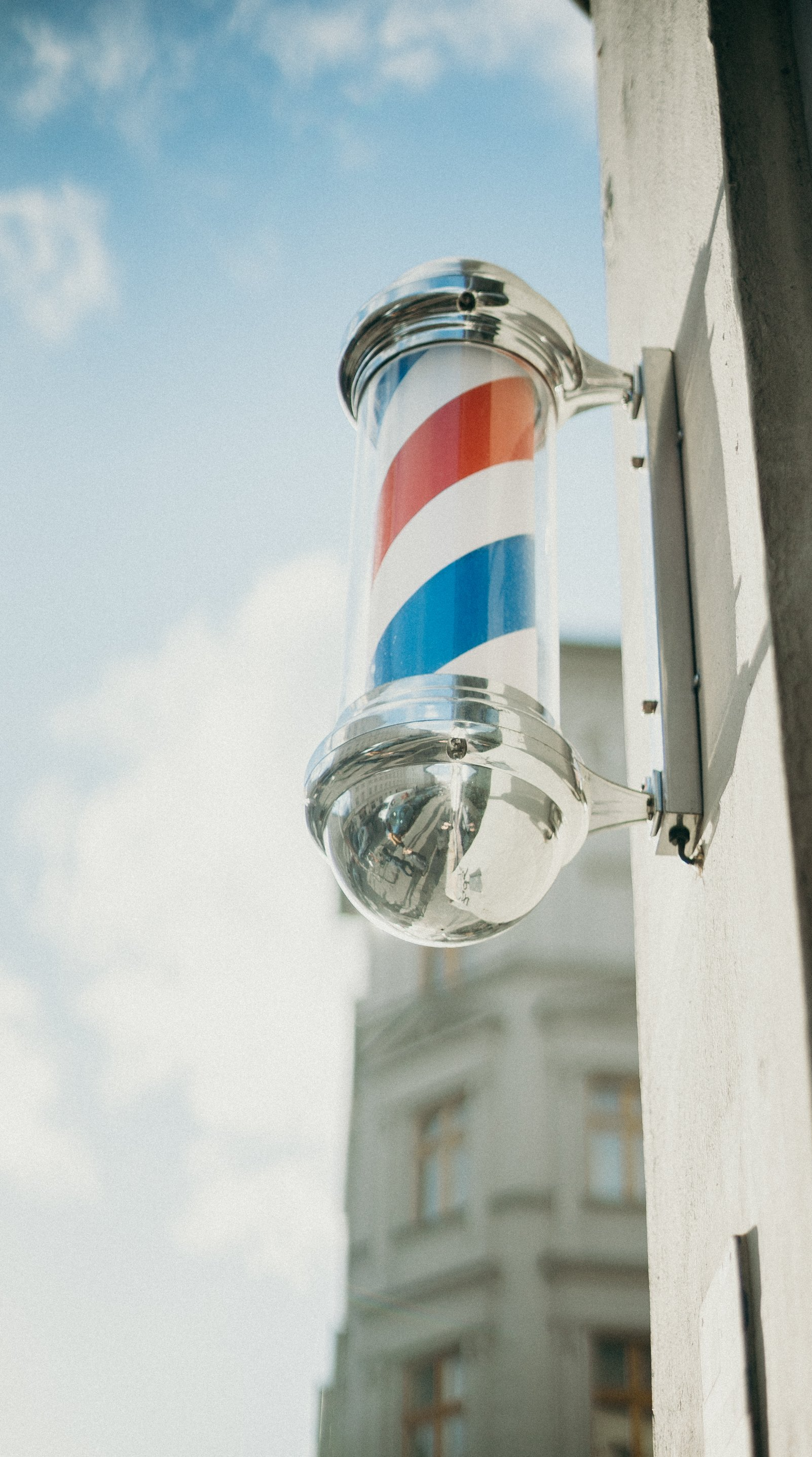 A barber pole is hanging on the side of a building.