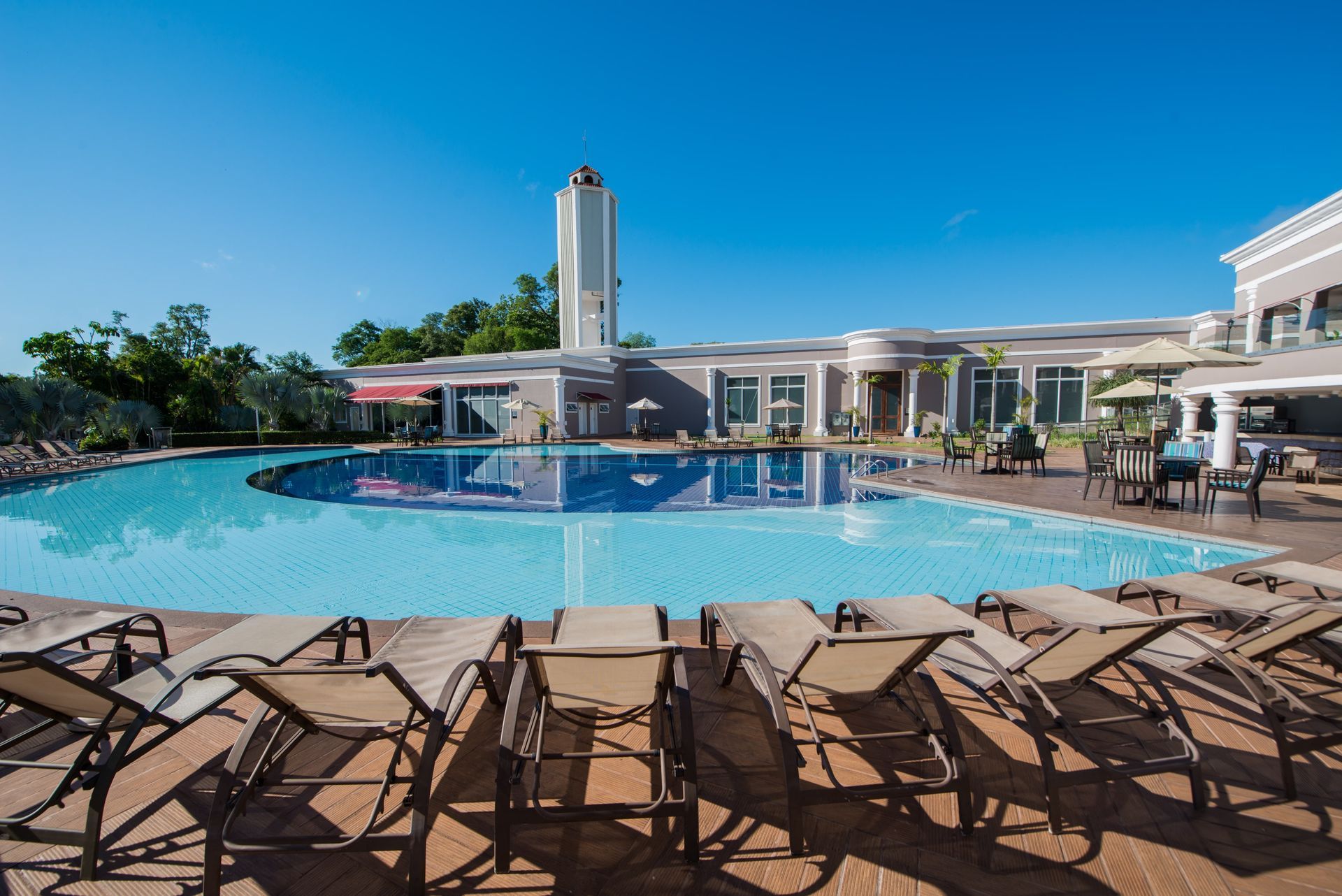 Uma grande piscina cercada por cadeiras de jardim e um edifício.