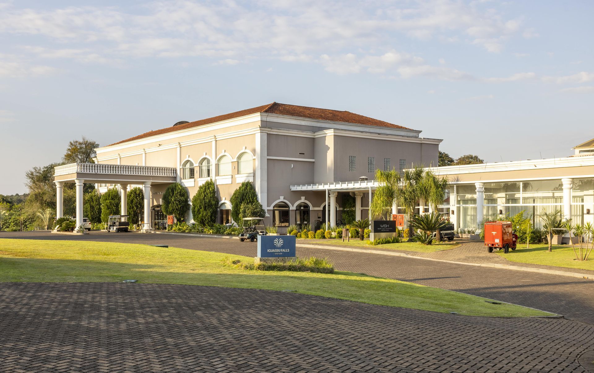 Um grande edifício branco com telhado de telhas vermelhas cercado por árvores e grama.