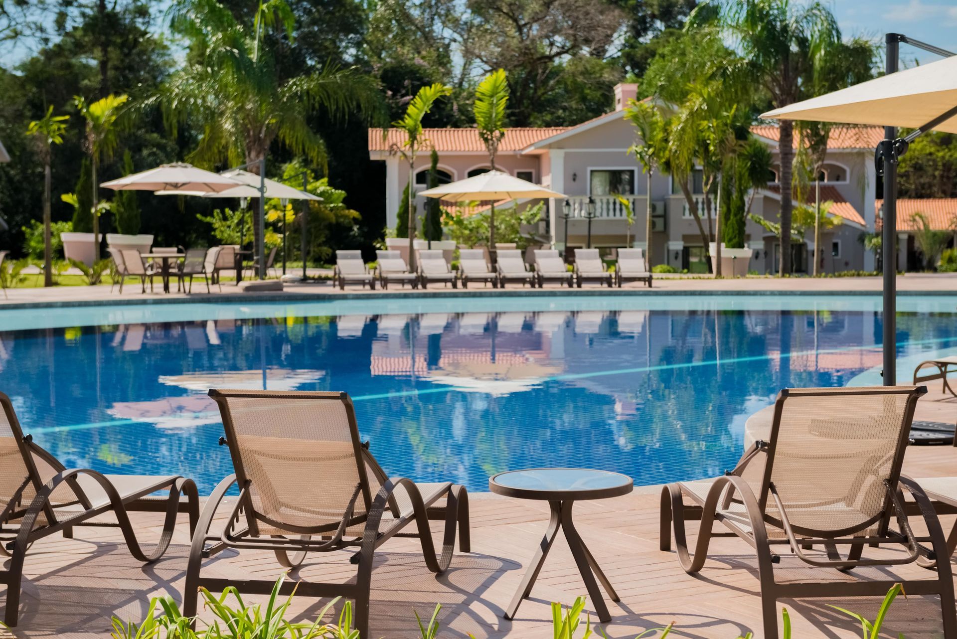 Uma grande piscina cercada por cadeiras, mesas e guarda-sóis.