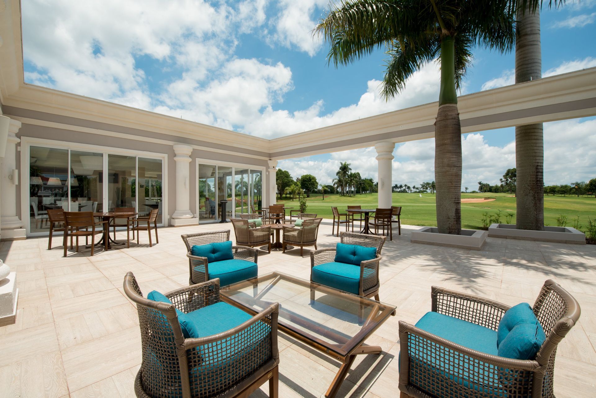 Um pátio com cadeiras, mesas e uma palmeira