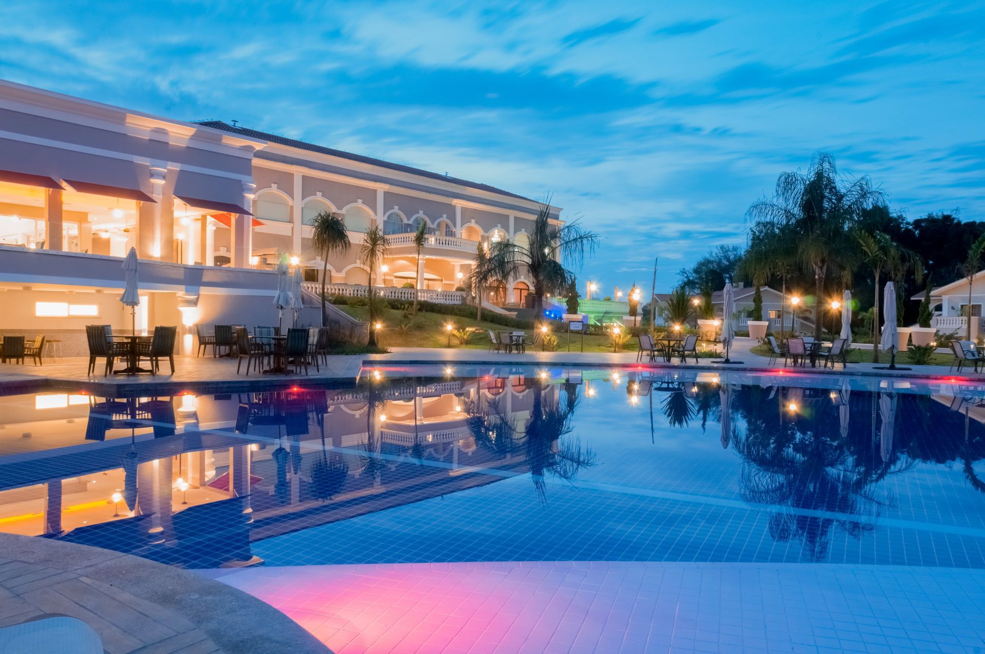 Uma grande piscina em frente a um hotel à noite.