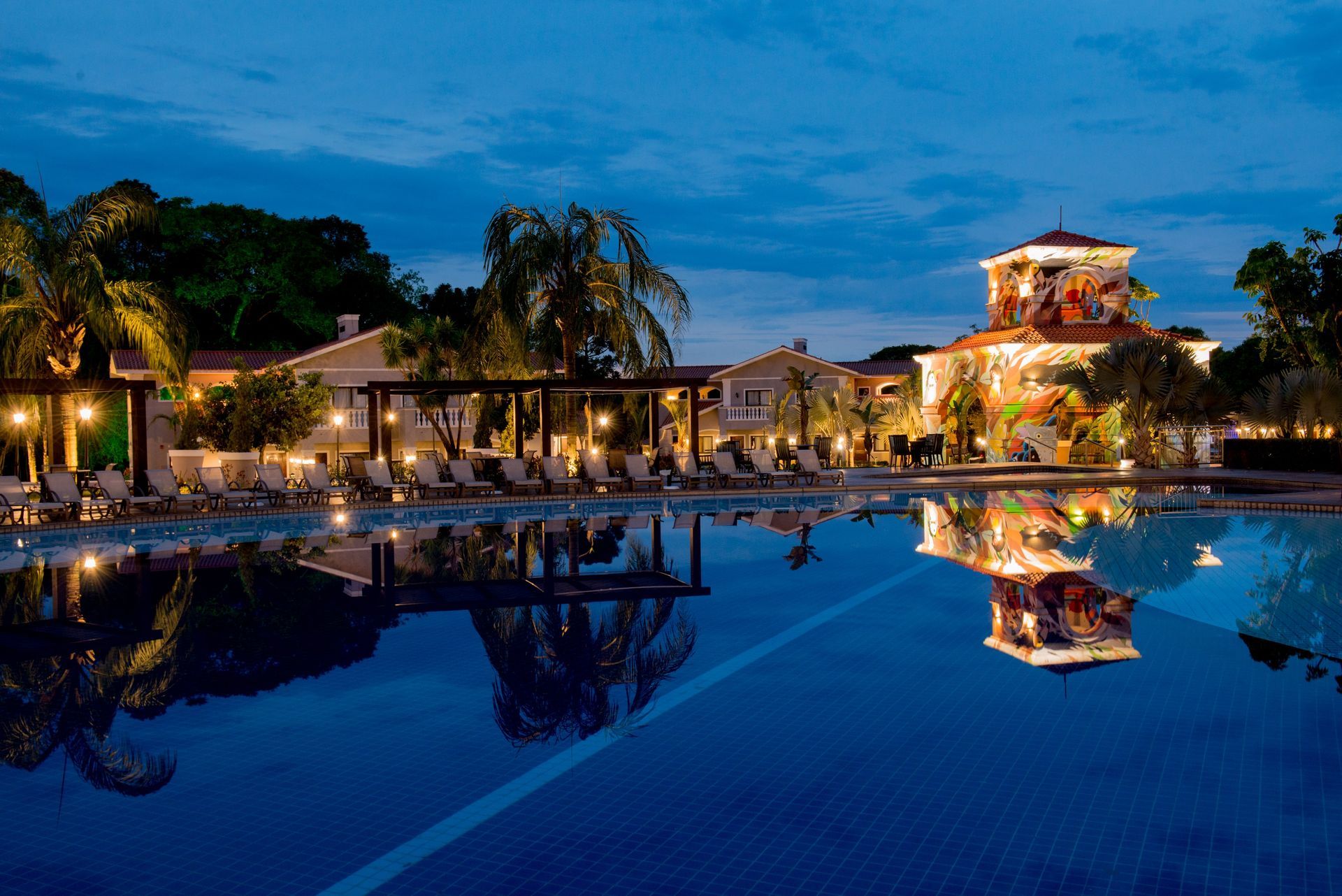 Uma grande piscina com um prédio ao fundo à noite