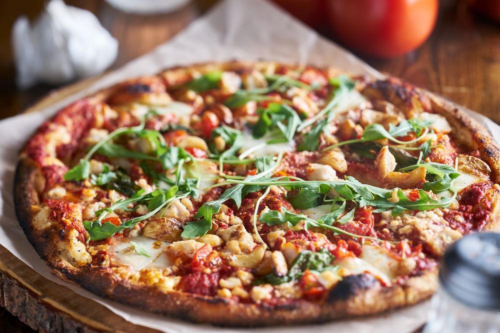A Pizza is Sitting on a Wooden Cutting Board on a Wooden Table — Michelangelos Pizza & Pasta in  Mount Louisa, QLD