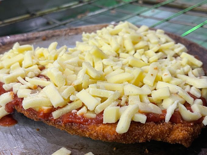 A Piece Of Chicken Covered In Sauce And Cheese On A Plate — Michelangelo's Pizza & Pasta in Kirwan, QLD