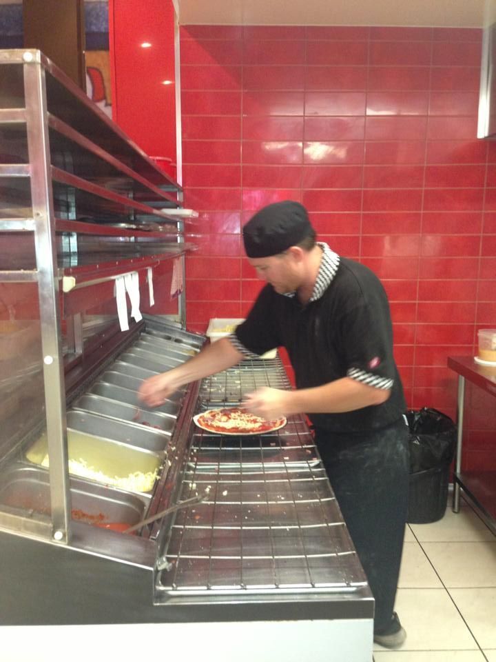 A Man is Preparing a Pizza in a Kitchen — Michelangelos Pizza & Pasta in  Burdell, QLD