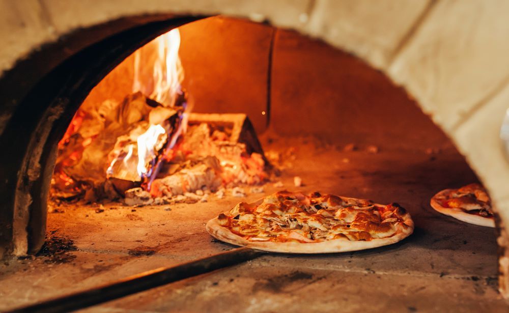 A Pizza is Being Cooked in a Wood Fired Oven — Michelangelos Pizza & Pasta in  Aitkenvale, NSW