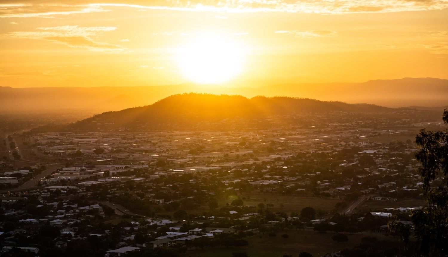 The Sun is Setting Over a City With Mountains in the Background — Michelangelos Pizza & Pasta in  Mount Louisa, QLD