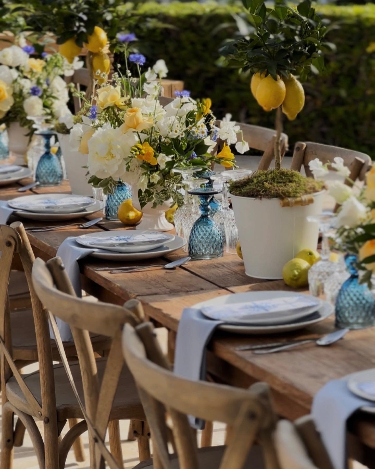A table with plates , glasses , vases and flowers on it.
