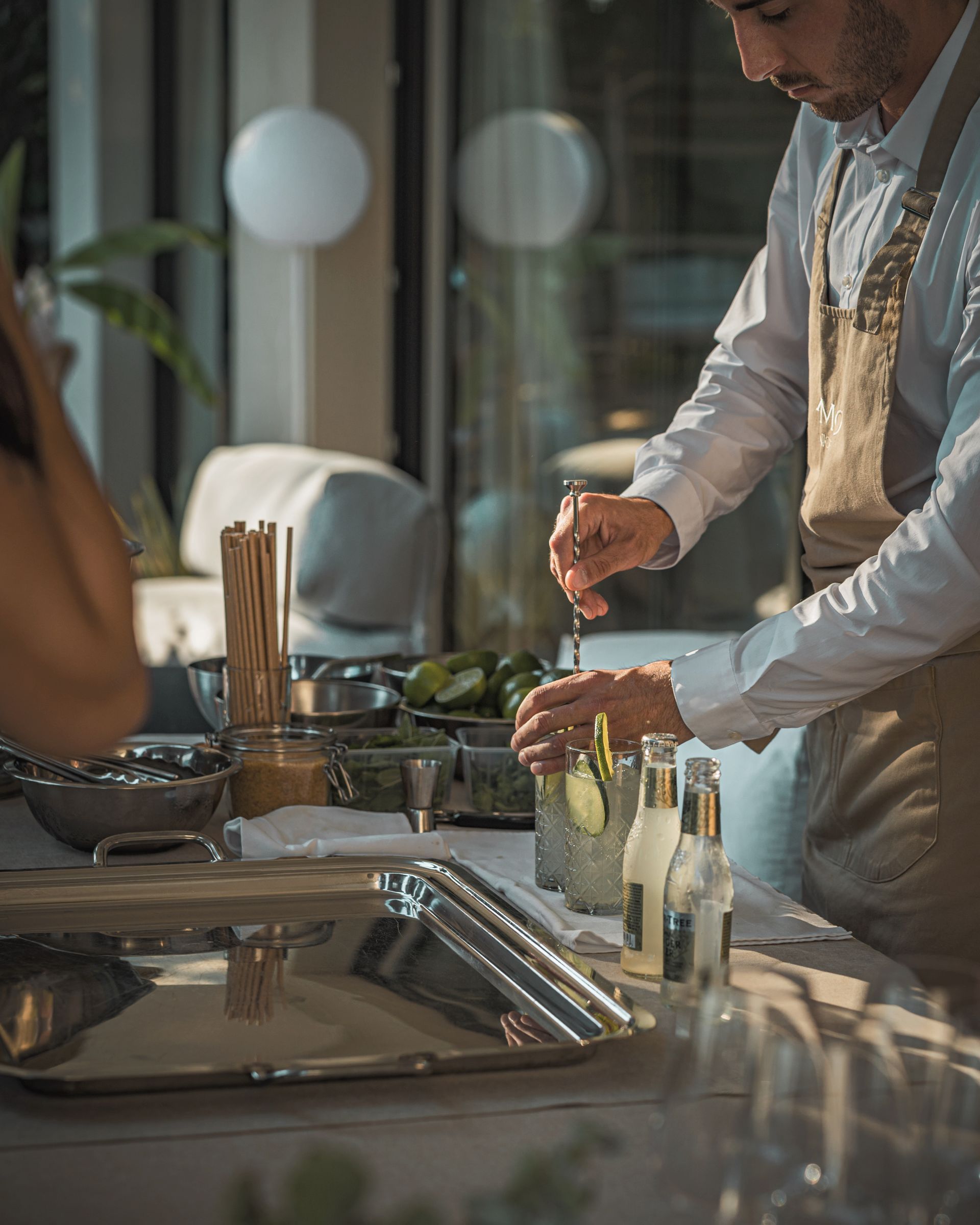 A man in an apron is preparing a drink at a table.