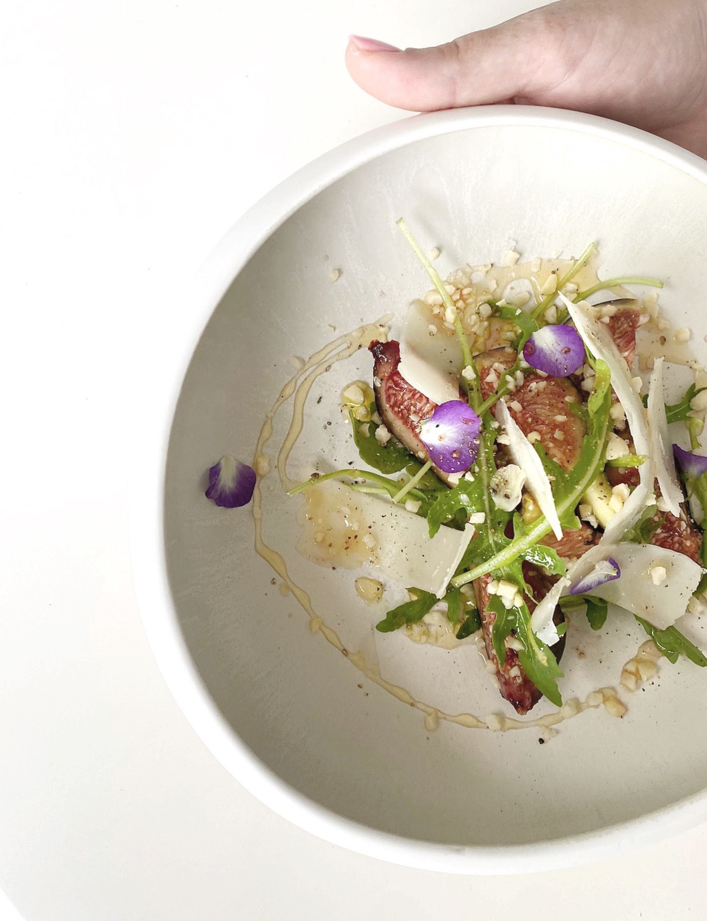 A person is holding a bowl of food with purple flowers on it
