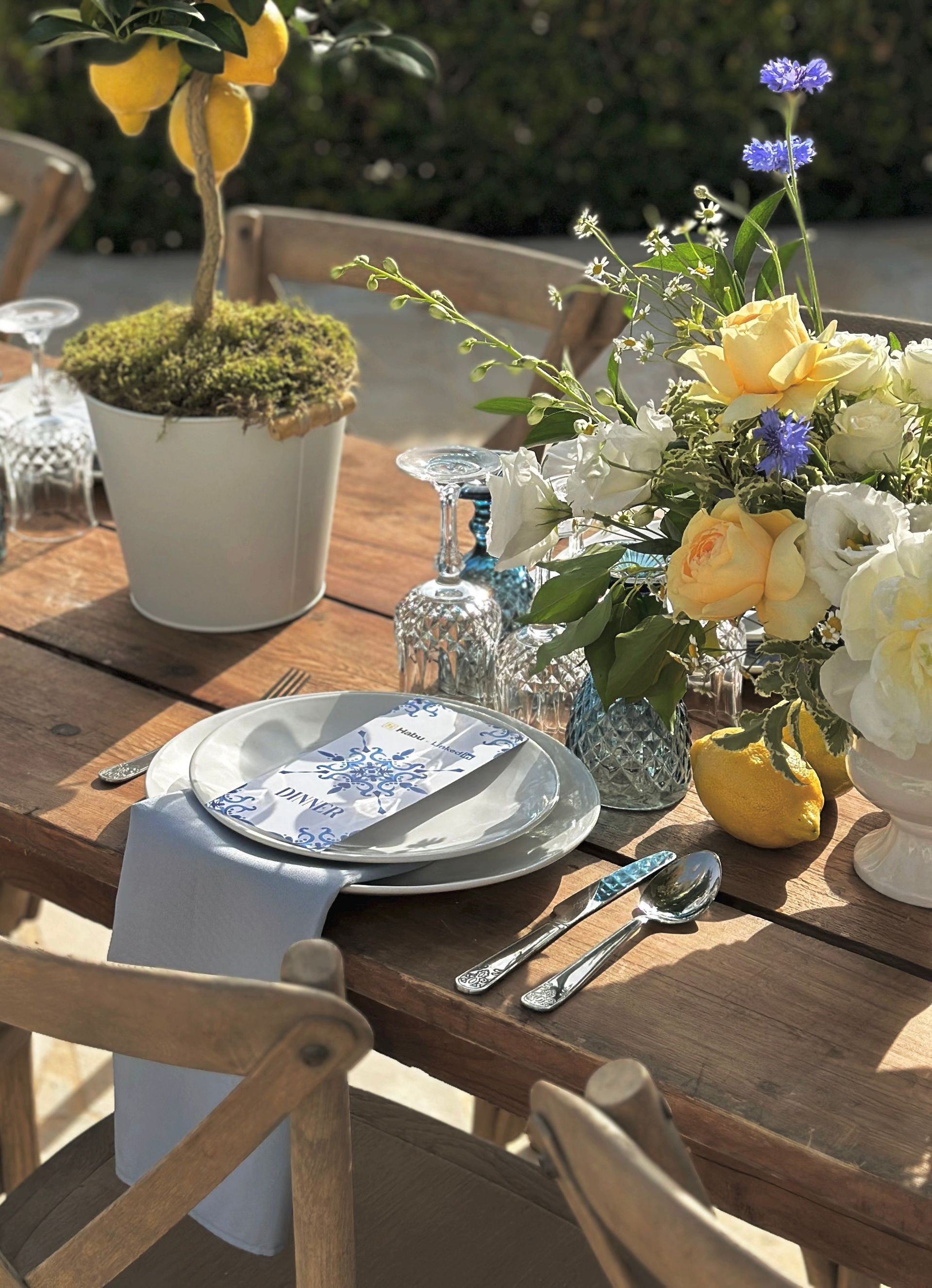 A wooden table with plates , utensils , and flowers on it.