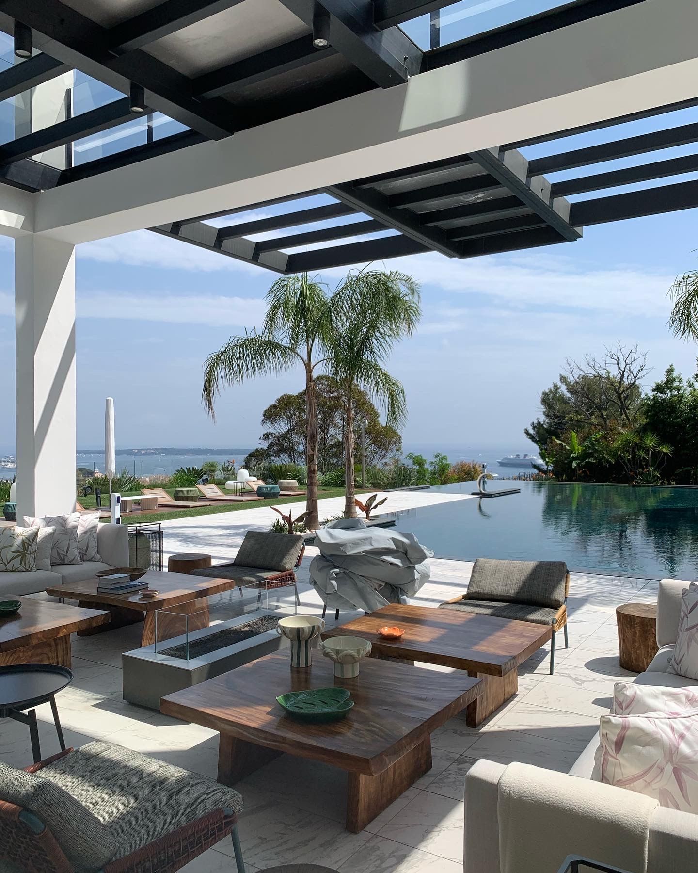 A living room with a lot of furniture and a swimming pool in the background.