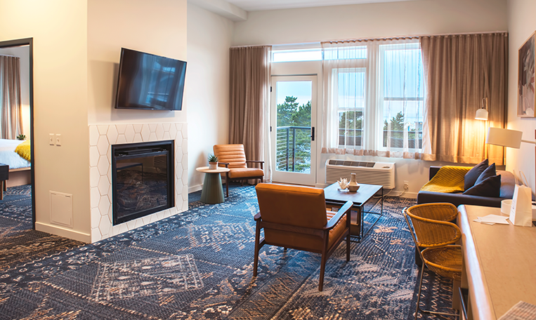 a living room in a hotel room with a fireplace and a flat screen tv .