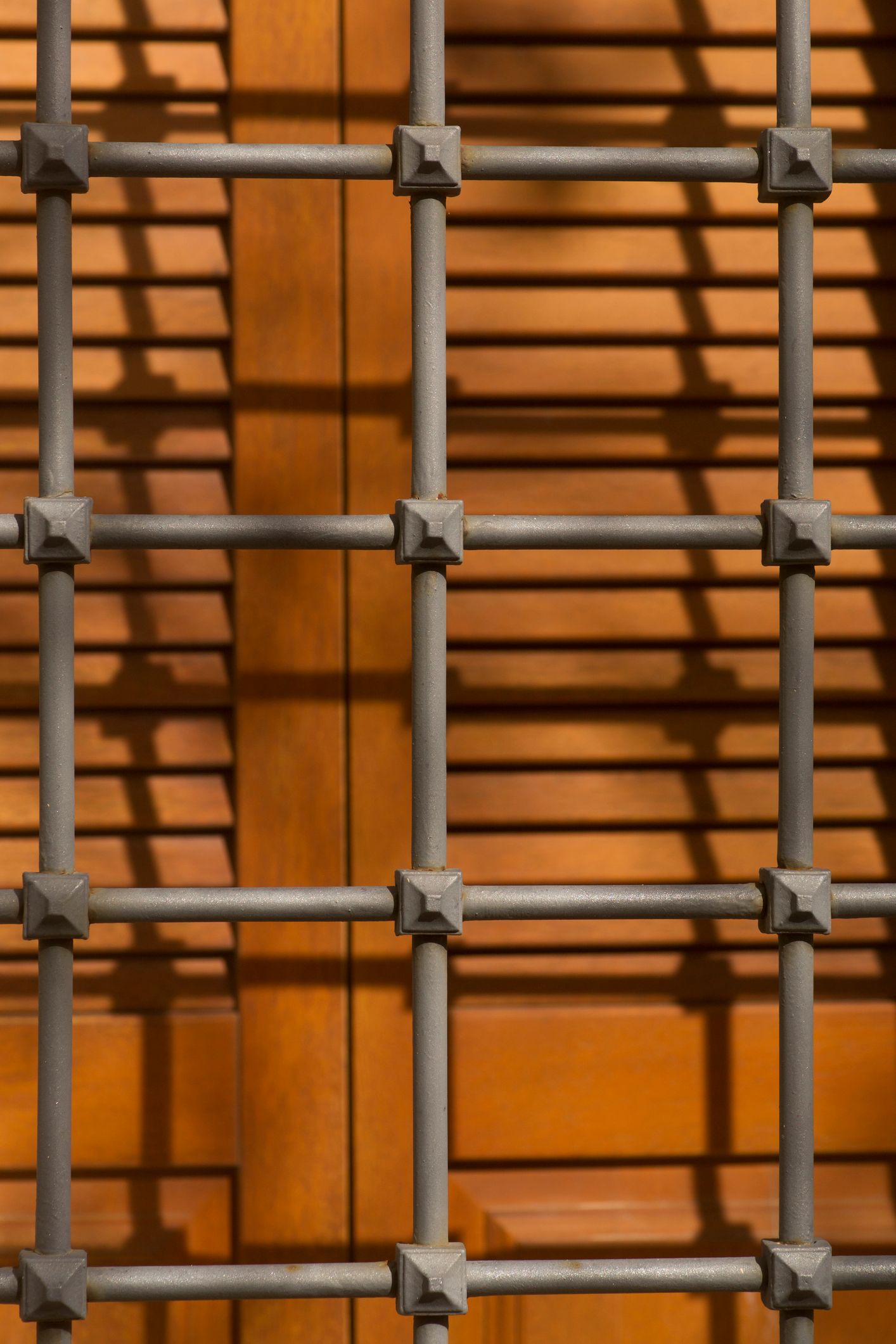 Lampione giallo e grate in ferro nero ornate su un edificio in pietra color cuoio.