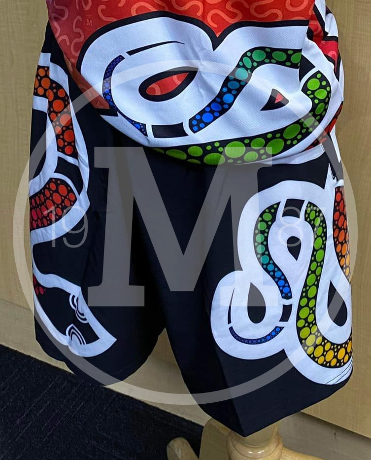 A mannequin wears black athletic shorts decorated with large, white, snake-like patterns filled with colorful dot art.