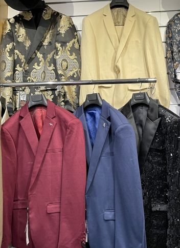 A collection of colorful, hand-knitted beanies with striped patterns arranged on a gray surface.