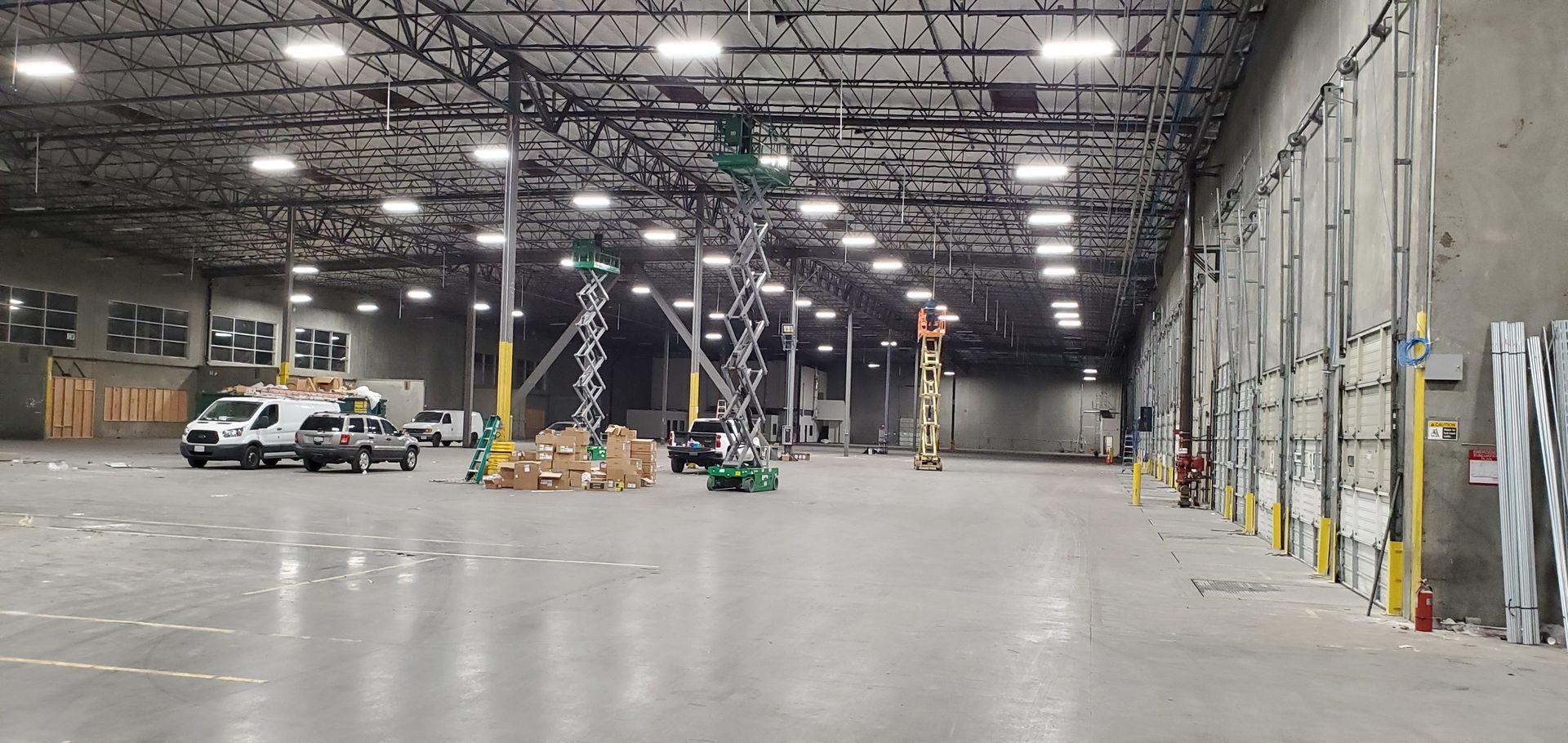 Interior of a large warehouse with vehicles and elevated machinery.