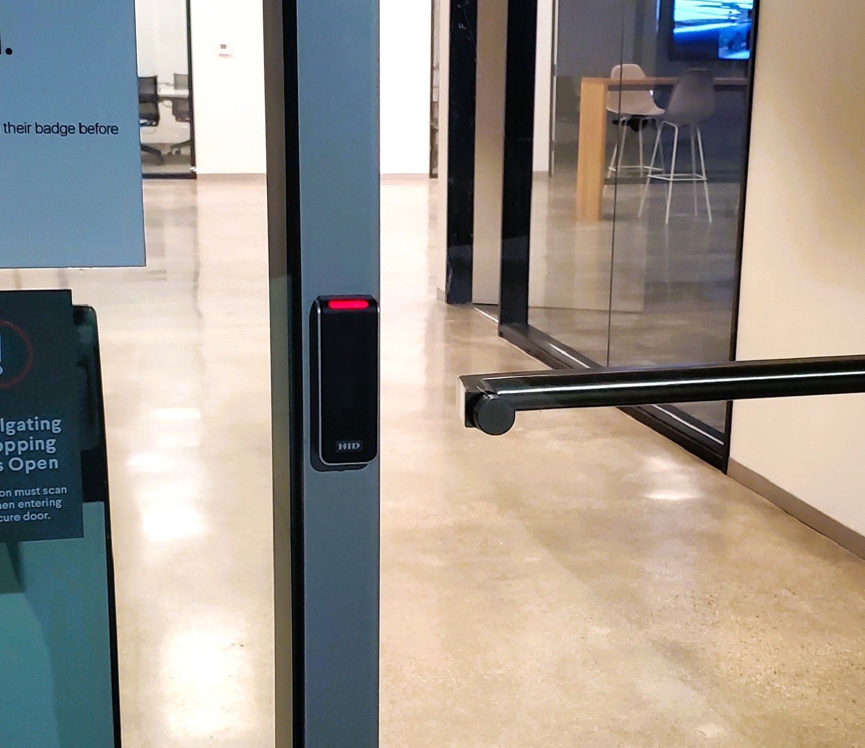 Door with a black card reader. Interior with glass walls and a bar handle.