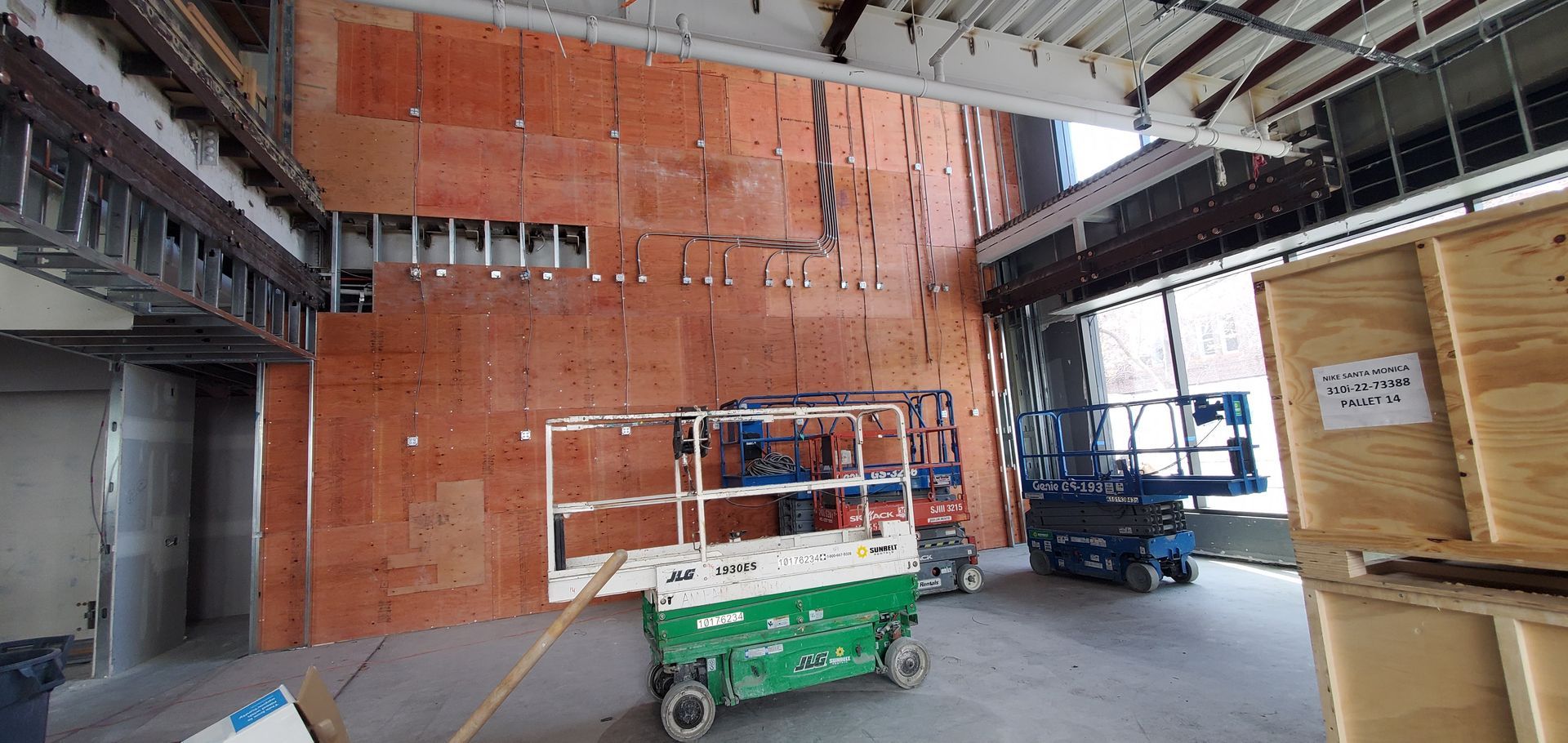 Interior construction site with lift equipment and exposed wall panels.