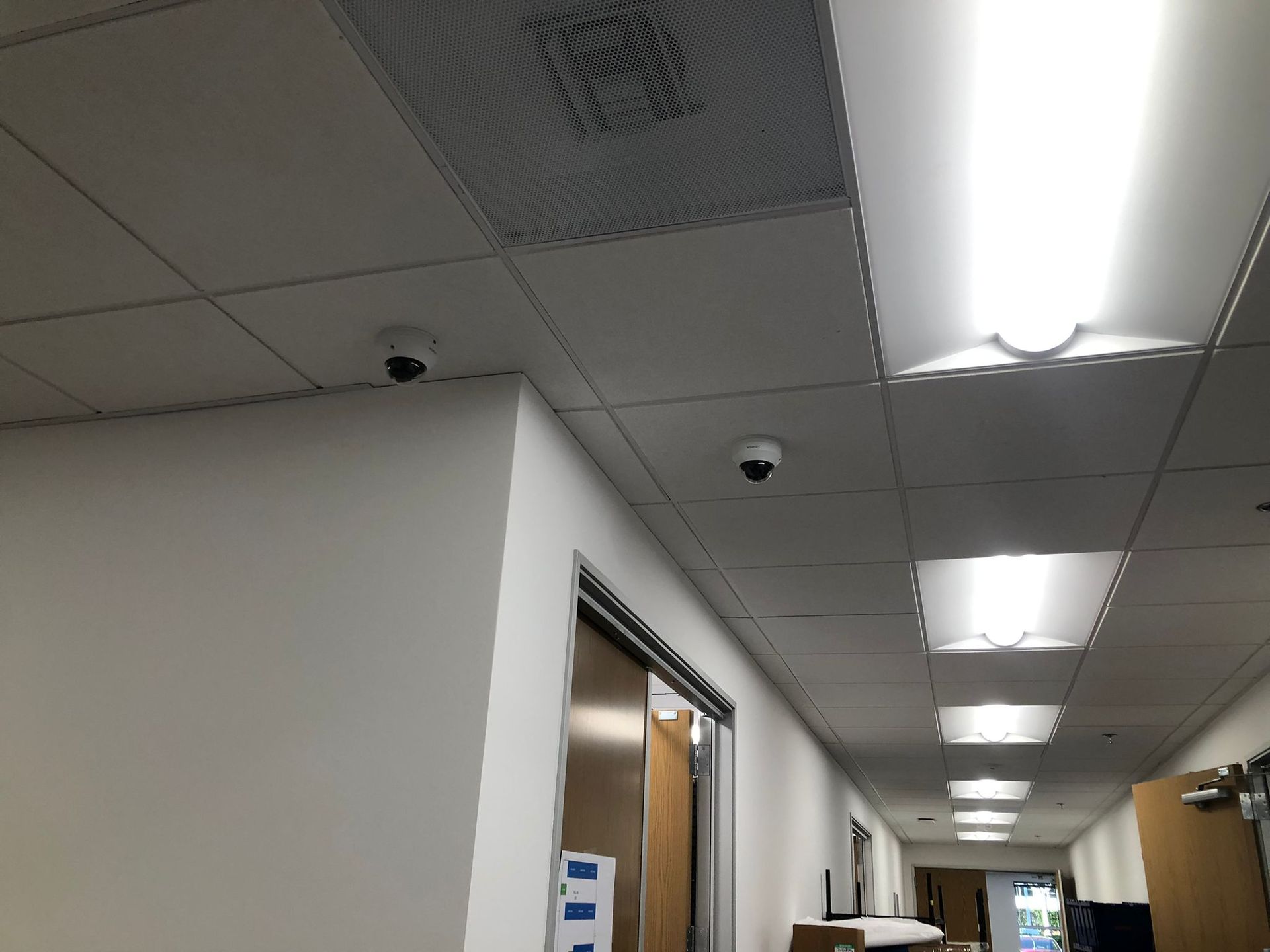 Hallway with white walls, ceiling lights, and two security cameras.