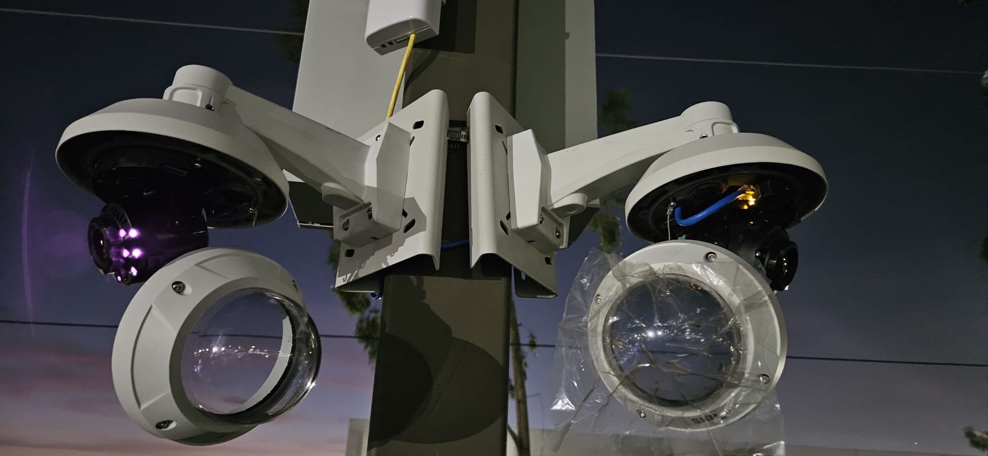 Two security cameras mounted on a pole, with a dark, blurred background.