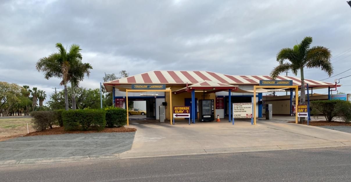A Building With A Red And White Striped Awning And Palm Trees In Front Of It — Emerald Car Wash In Emerald, QLD