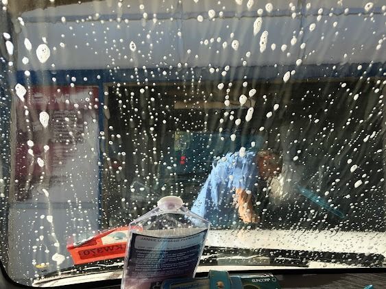 A Man Is Cleaning The Windshield Of A Car — Emerald Car Wash In Emerald, QLD