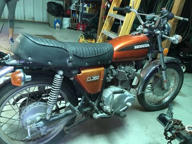 Orange Honda motorcycle parked in a garage, side view with black seat and chrome details