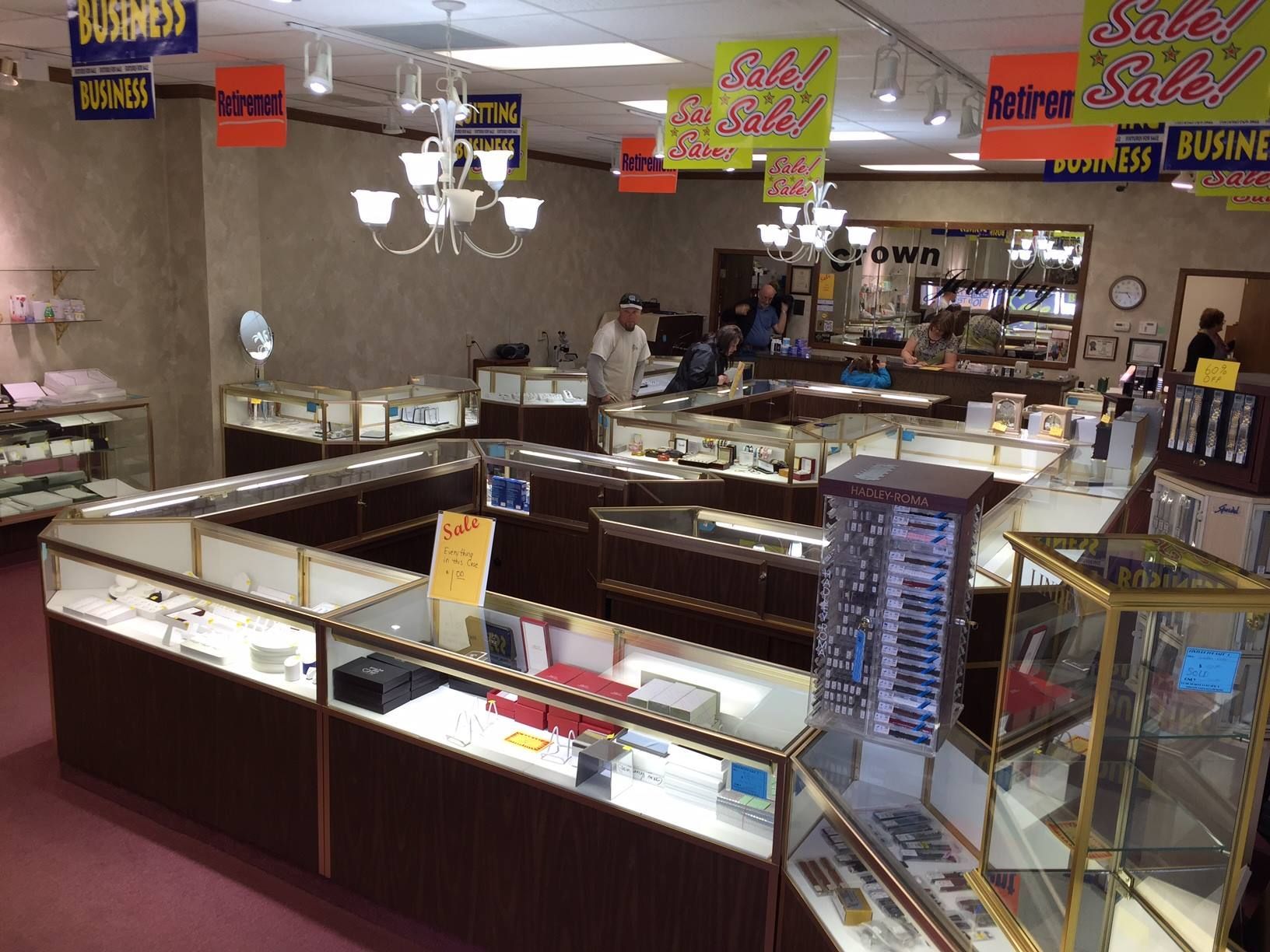 Jewelry store interior with display cases, sale signs, and a salesperson behind the counter