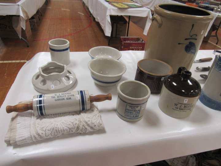 Assorted kitchenware and pottery items displayed on a white table at a craft market.