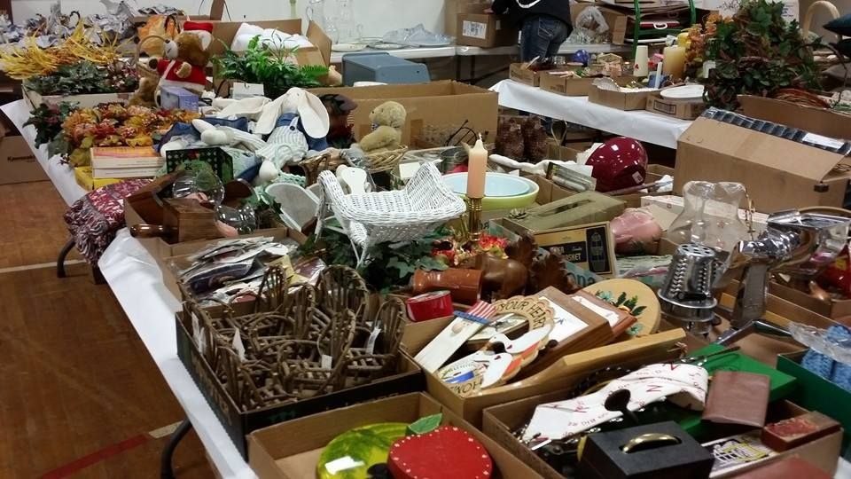 Tables crowded with assorted holiday decorations, wrapped gifts, and craft items in a room