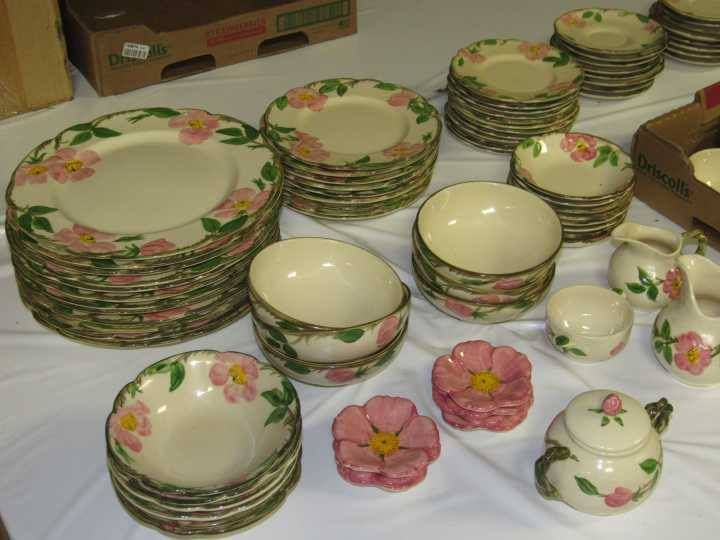 Stacked floral-patterned dishes and bowls on a table with pink flower-shaped accents