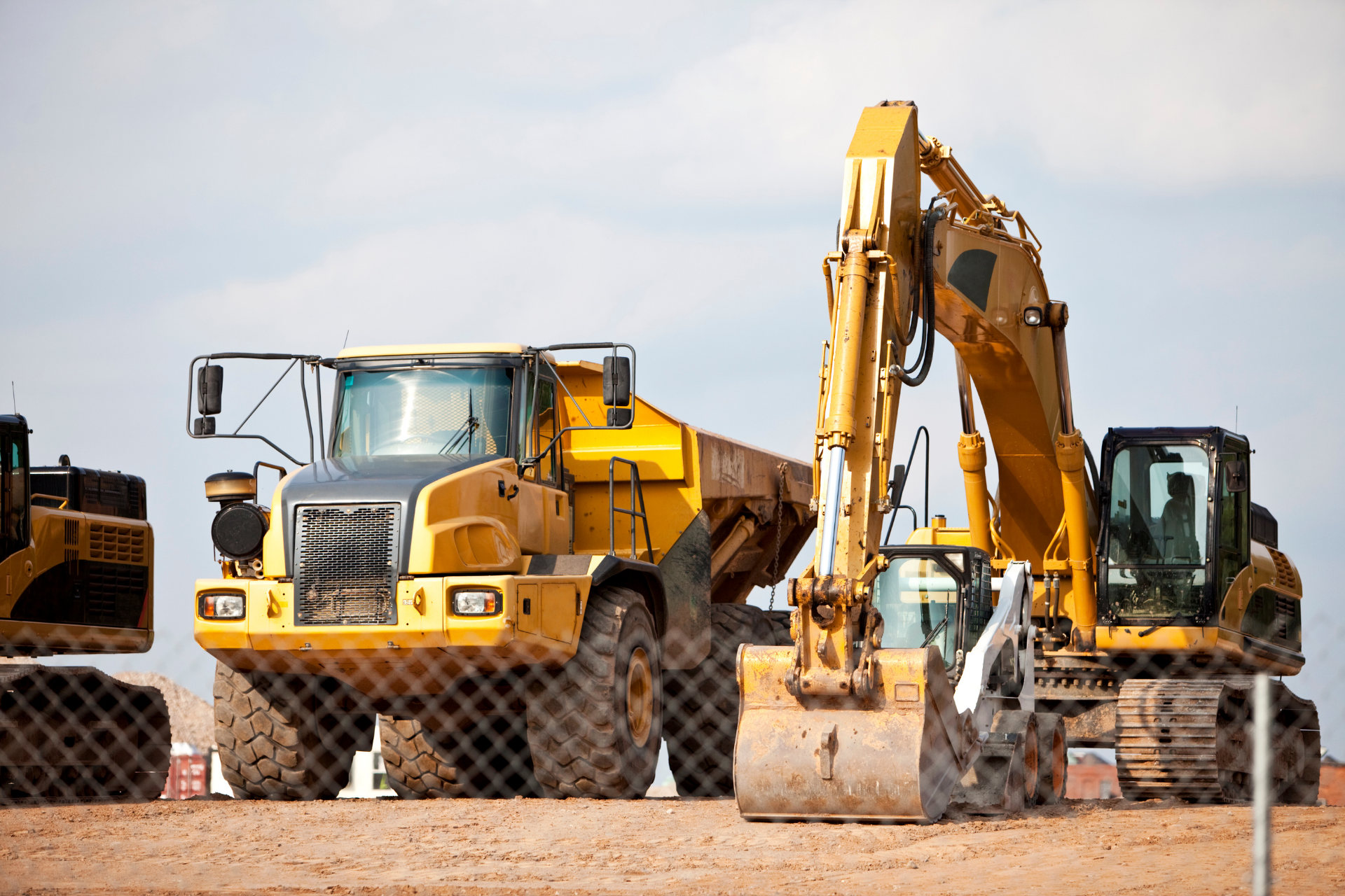 Two excavators digging earth in a construction zone, kicking up dust.