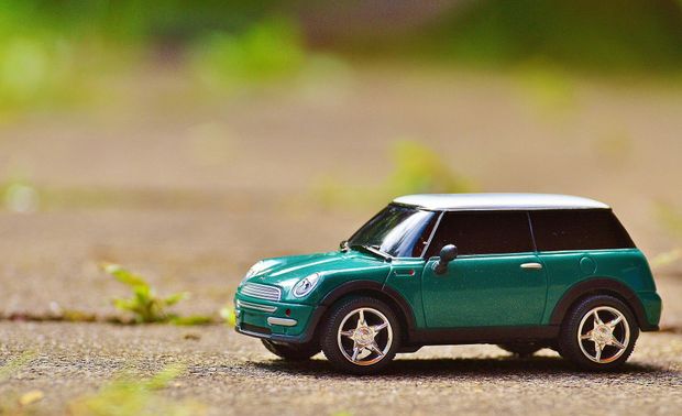 A green toy car is sitting on the ground.