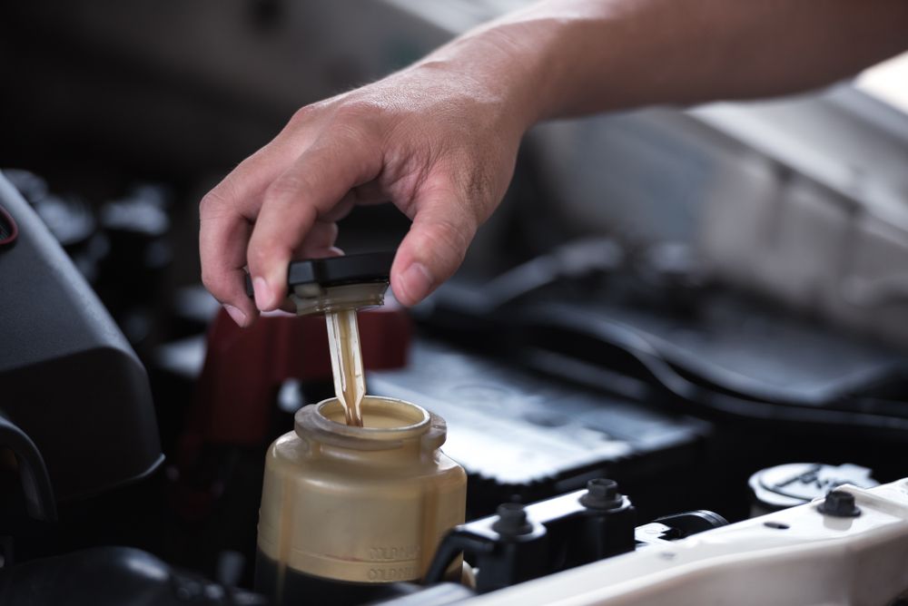 Hand Opening a Power Steering Fluid Reservoir in a Car Engine Bay — Bob Kolln Automotive In Toukley, NSW