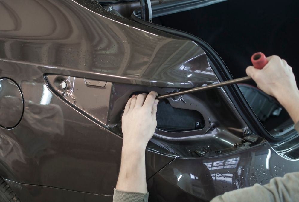 Person Using a Tool to Work on a Car's Trunk — Bob Kolln Automotive In Woongarrah, NSW