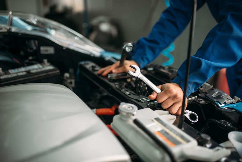 Mechanic in Blue Jumpsuit Using a Wrench on a Car Engine — Bob Kolln Automotive In Woongarrah, NSW