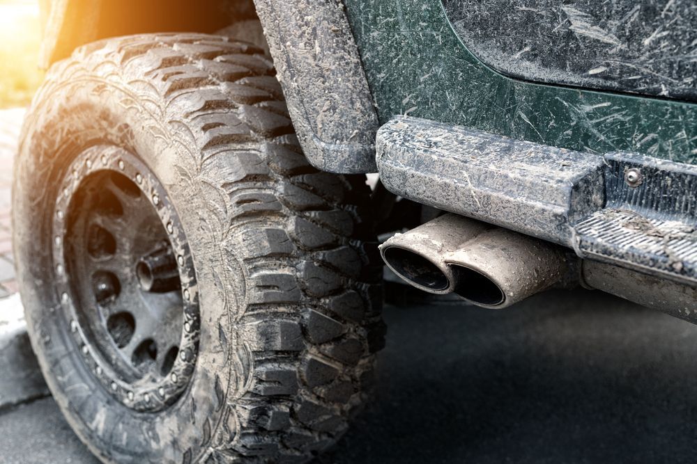 Dirty, Off-road Vehicle Tire and Exhaust Pipes; the Car is Covered in Mud — Bob Kolln Automotive In Toukley, NSW