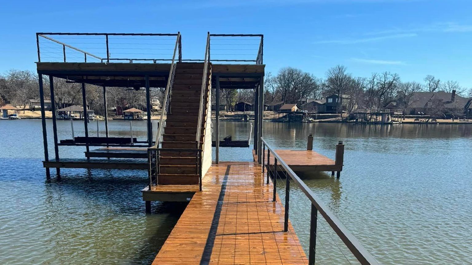 A dock with stairs leading up to a house on a lake.