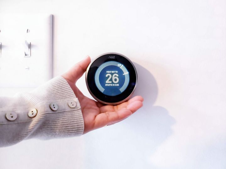 a person is holding a nest thermostat in their hand