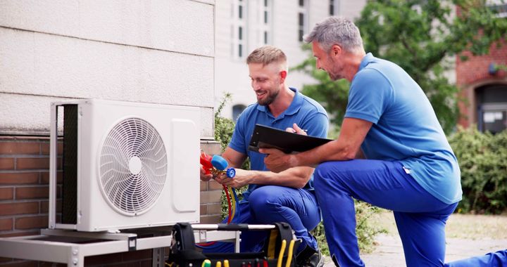 two men are working on an air conditioner outside of a building