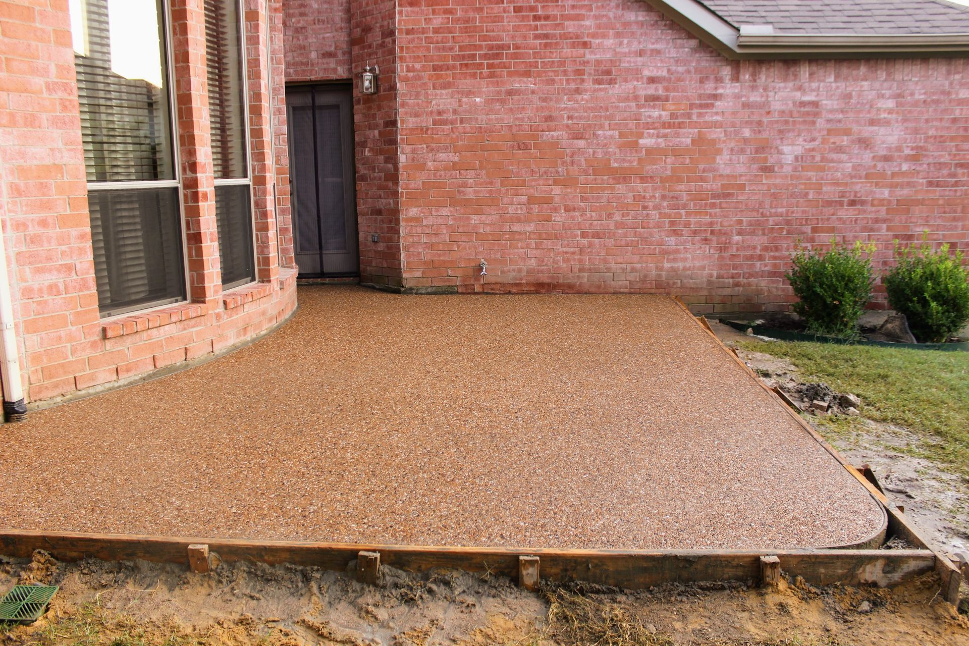 A brick house with a concrete patio in front of it.