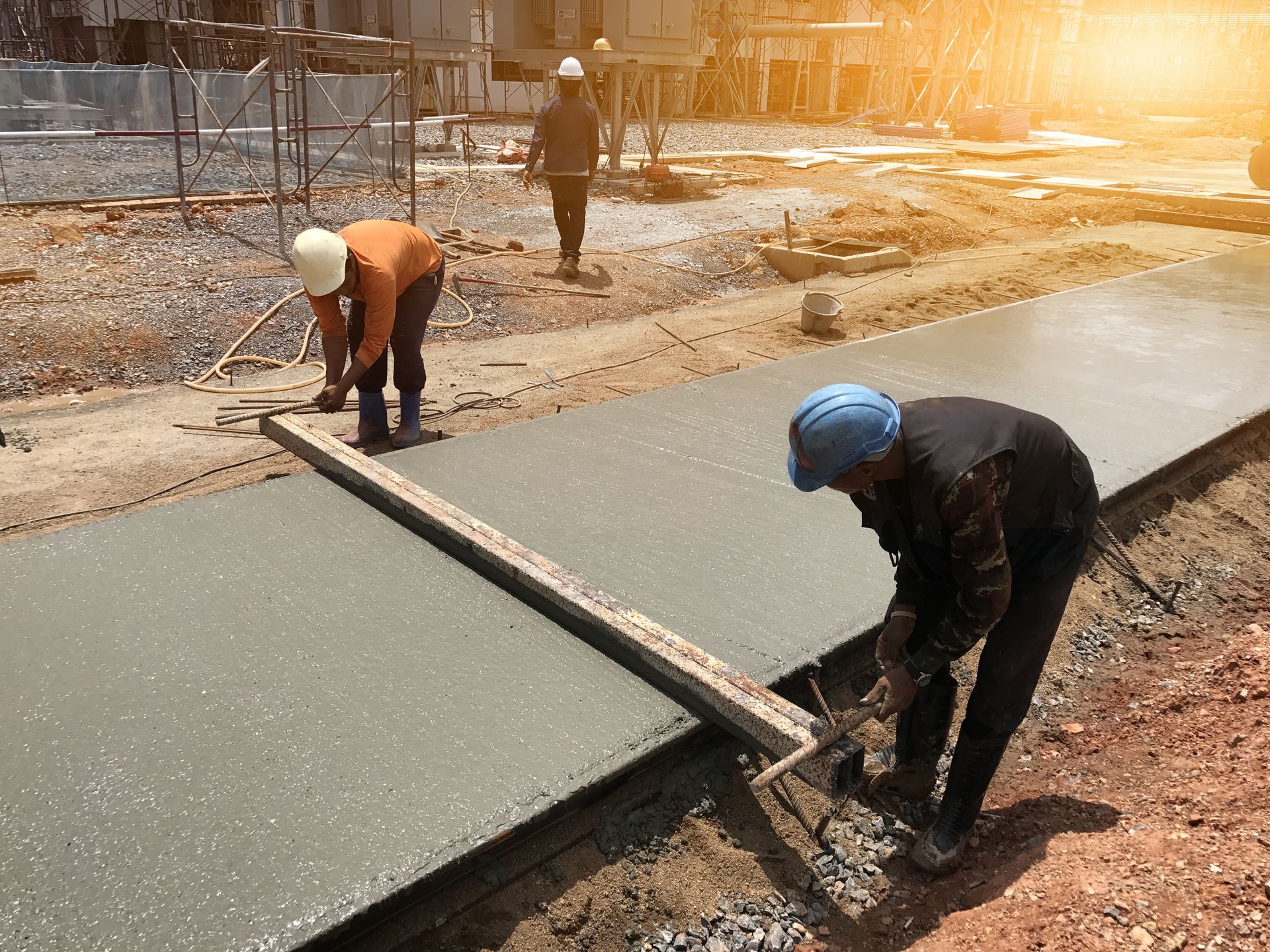 A group of construction workers are working on a concrete walkway.