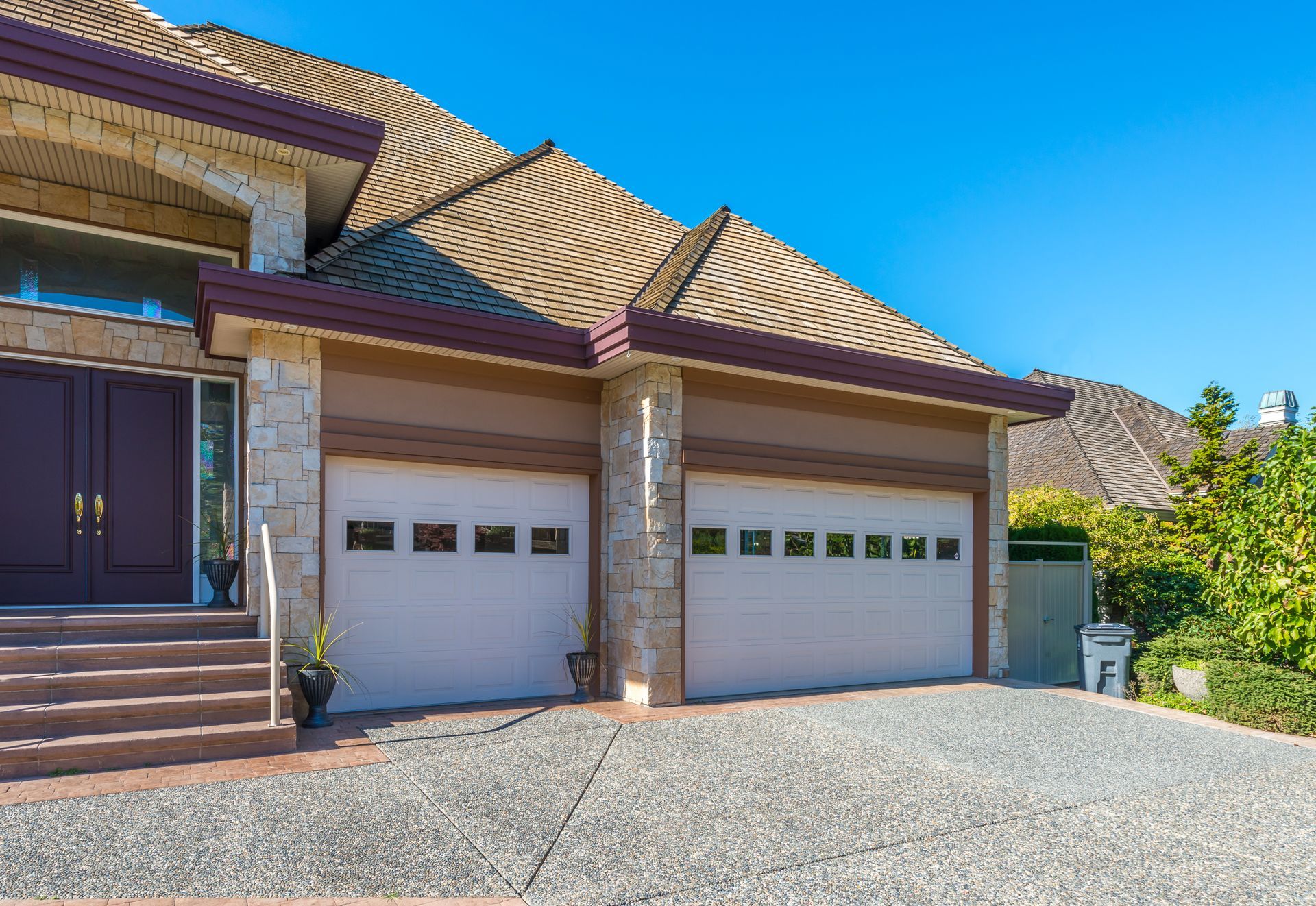 A large house with two garage doors and a concrete driveway.