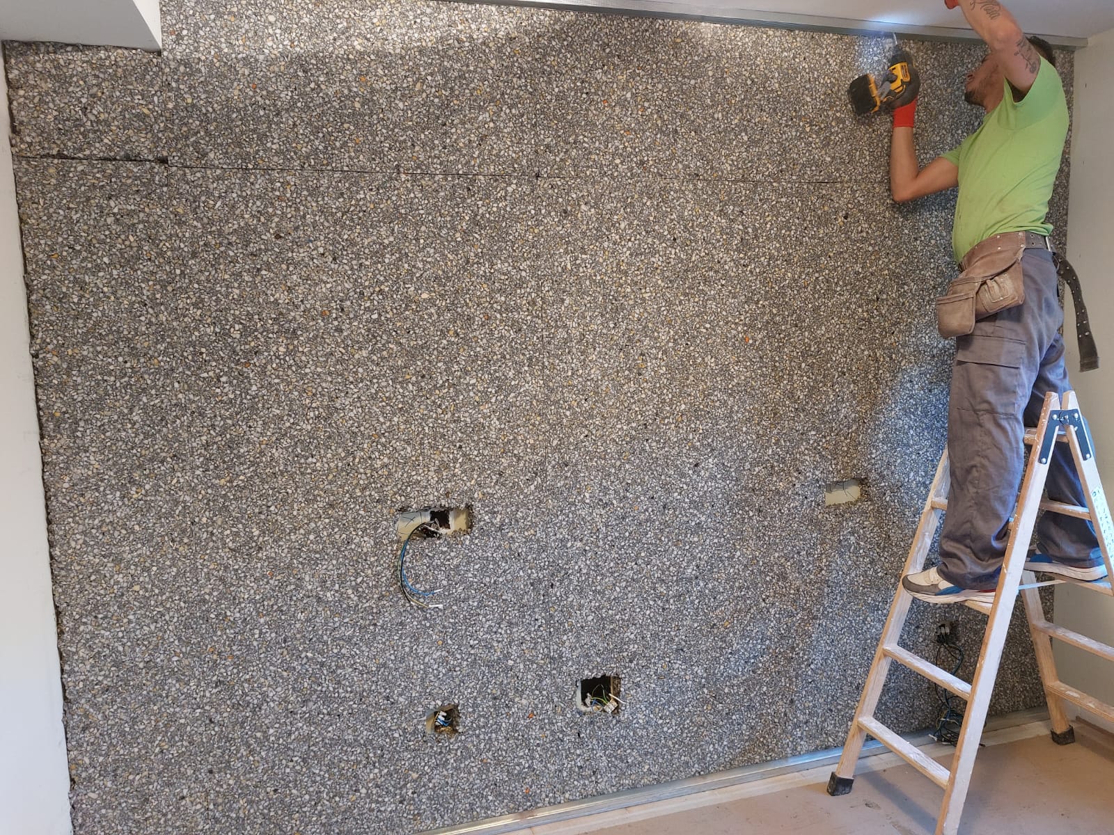 Un hombre está parado en una escalera trabajando en una pared.