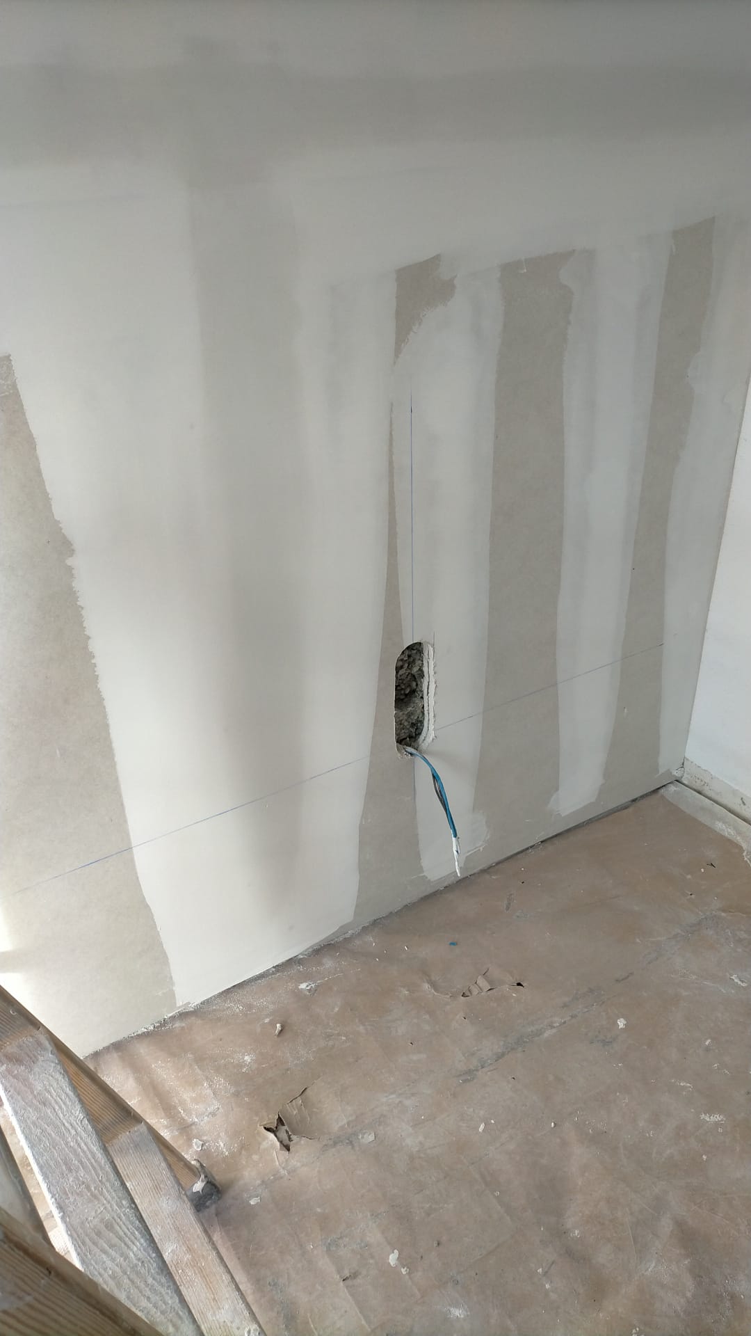 Una habitación con un agujero en la pared y un cepillo en el suelo.