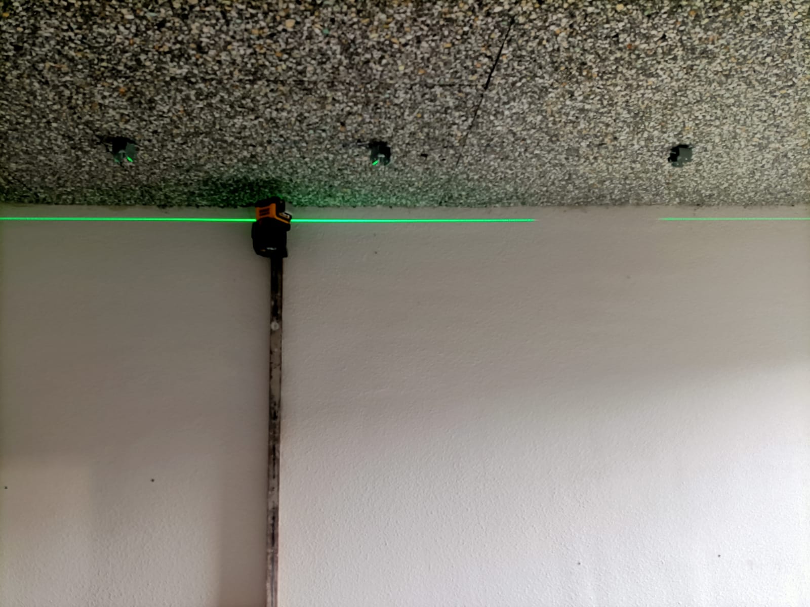Una persona está midiendo una pared con un láser verde.
